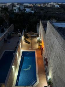 a swimming pool on the side of a house at night at Tal-Bir Farmhouse in Nadur