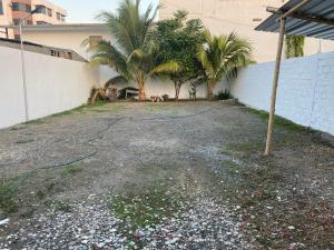 a gravel driveway with palm trees and a building at Hostal Casa Latina in Manta