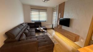 a living room with a brown leather couch and a television at Lux apartment Sky Central Residence Zlatibor in Zlatibor