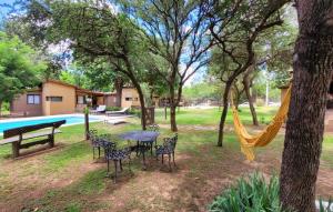 eine Hängematte in einem Park mit einem Tisch und Stühlen in der Unterkunft CABAÑAS SUKHA in Santa Rosa de Calamuchita