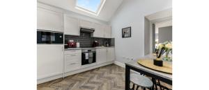 uma cozinha com armários brancos e uma mesa em Newly Renovated 1BD Flat Perfect for Travellers em Romford