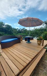 a wooden deck with a bench and an umbrella at Pousada Siroba Beira Rio in Morretes