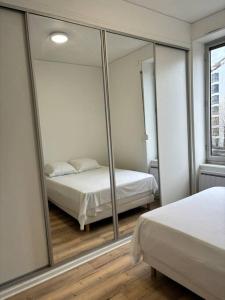 - une chambre avec un lit et un grand miroir dans l'établissement T2 à louer à Villeurbanne, à Villeurbanne