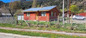 une petite maison avec une clôture devant elle dans l'établissement Cabañas La Plaza, à Bahía Murta