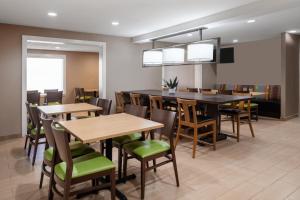 uma sala de jantar com mesas e cadeiras de madeira em Garner Hotel Macon West, an IHG Hotel em Macon