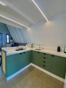 a kitchen with green cabinets and a sink at Chalé Pé do Morro in Penha
