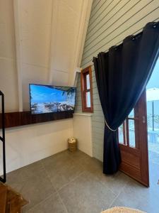 um quarto com uma televisão de ecrã plano e uma janela em Chalé Pé do Morro em Penha