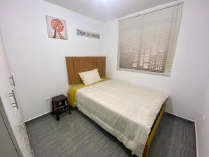 ein kleines Schlafzimmer mit einem Bett und einem Fenster in der Unterkunft Acogedora Casa cerca a la playa in Pisco