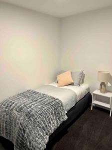 ein Schlafzimmer mit einem Bett mit einer Decke und einer Lampe in der Unterkunft Stylish Sandy Bay Apartment in Sandy Bay