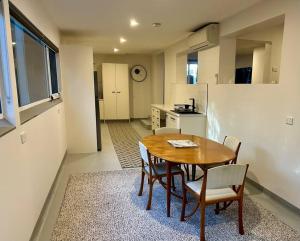 cocina y comedor con mesa de madera y sillas en Stylish Sandy Bay Apartment en Sandy Bay