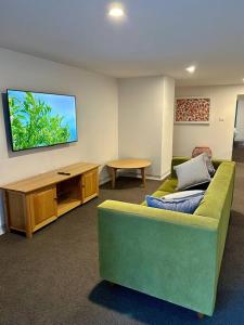 a living room with a green couch and a flat screen tv at Stylish Sandy Bay Apartment in Sandy Bay