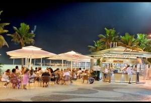 un groupe de personnes assis à des tables sous des parasols sur la plage dans l'établissement Loft Praia de Copacabana, à Rio de Janeiro