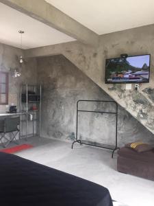 1 dormitorio con 1 cama y TV en la pared en Suítes classic, en Búzios