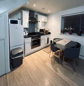 een keuken met een tafel en een witte koelkast bij Guest House Nikol in Sherborne Saint John
