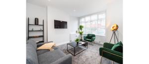 a living room with a gray couch and two green chairs at Hassle-Free & Handsome Brand-New 3-Bed Home in Manchester