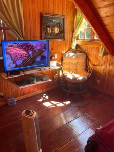 uma sala de estar com uma televisão e uma cadeira e uma cadeira em La Cabaña: Descanso y Naturaleza em Cartago