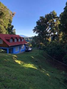 uma casa com um telhado vermelho num campo verde em La Cabaña: Descanso y Naturaleza em Cartago