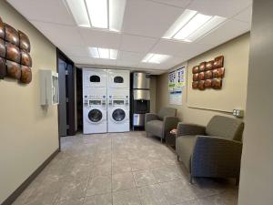eine Waschküche mit Waschmaschine, Trockner und Stühlen in der Unterkunft Coast Calgary Downtown Hotel & Suites by APA in Calgary
