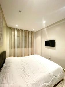 sypialnia z dużym białym łóżkiem i telewizorem z płaskim ekranem w obiekcie Luxurious Apartment Center Agdal Rabat w mieście Rabat