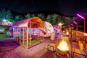 Hongcheon Botopia Healing Park في هونغتشان: شرفة مع خيمة ومخيم في الليل