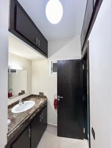 a bathroom with a sink and a black door at Appartement Duplex élégant et calme Marrakech Menara in Marrakesh