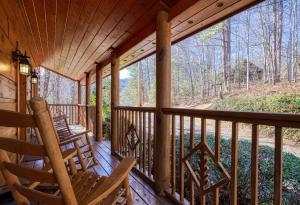 賽維爾維爾的住宿－Secluded Hideaway cabin，一个带摇椅的门廊,享有树林的景色