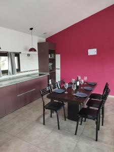 a dining room with a red wall and a table and chairs at Estancia Borke - Carlos Paz in Estancia Vieja