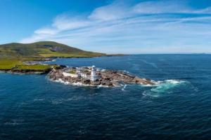 an island in the ocean with a lighthouse on it at Harbor View in Valentia Island