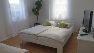 a white bed with green pillows in a room at Moderner Fachwerktraum in Uetze