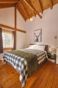 ein Schlafzimmer mit einem Bett mit einer karierten Decke in der Unterkunft Marble Saltbox ~ hot tub in Steady Brook