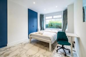 een slaapkamer met een bed, een stoel en een raam bij Luxurious 2 bedroom flat with parking and garden, 5 mins walk to train station and bus stop opposite property in Londen