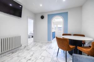 a dining room with a white table and chairs at Luxurious 2 bedroom flat with parking and garden, 5 mins walk to train station and bus stop opposite property in London
