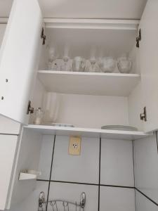 een keuken met witte kasten en planken met borden bij Loft completo na Asa Sul próximo da P Federal ENAP LBV Aeroporto CASV , Rodov Interestadual e academia da PM in Brasilia