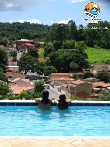 two women sitting in a swimming pool with a view at Pousada Espaço Cosmos in Águas da Prata