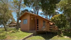 une petite maison dans un champ arboré dans l'établissement Chales Boa Vista, à Monte Verde