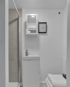 a white bathroom with a sink and a shower at The Green Room in Sydenham