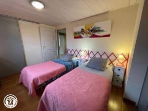 two beds in a room with pink and blue sheets at Gîte charmant au bord de l'eau avec canoës, terrasse et jardin à Damvix, au cœur du Marais Poitevin. - FR-1-426-354 in Damvix