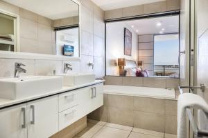 un bagno con due lavandini, una vasca e una finestra di Monaco Caloundra a Caloundra