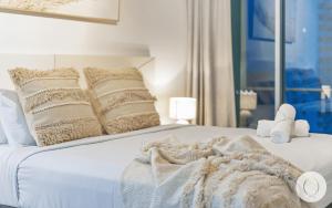 a white bed with a blanket and pillows on it at Wings Apartments - QStay in Gold Coast