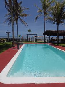 a large swimming pool with palm trees on the beach at Pousada Flor de Elisa frente a praia in Caraíva