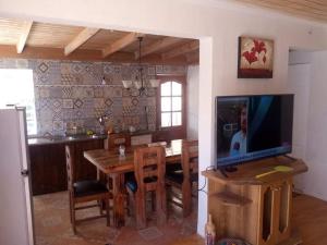 cocina y comedor con mesa y TV en Casa de campo, en Pichilemu