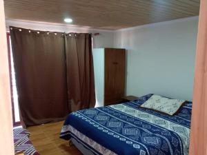 1 dormitorio con 1 cama con edredón azul en Casa de campo, en Pichilemu