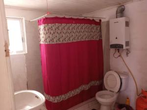baño con cortina de ducha roja y aseo en Casa de campo, en Pichilemu