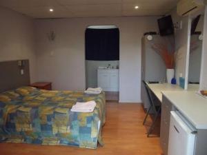 Schlafzimmer mit einem Bett, einem Schreibtisch und einem Waschbecken in der Unterkunft Leo Hotel Motel in Clermont