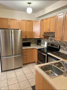 a kitchen with wooden cabinets and a stainless steel refrigerator at Cozy home in Brampton (Mt pleasant Go station) in Brampton