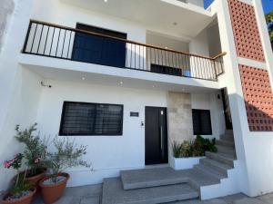 una casa blanca con escaleras y una puerta negra en Departamentos DOS21, en Mazatlán