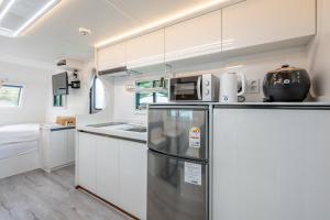 uma cozinha com armários brancos e um frigorífico em Gapyeong Olden Caravan & Pension - Pet Friendly em Gapyeong
