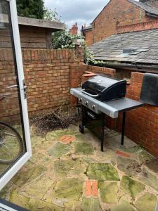 una parrilla sentada en un patio junto a una pared de ladrillo en Chart Cottage, en Stanmore