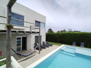 a swimming pool with a hammock and a house at Casa de playa en jose ignacio uruguay. in José Ignacio