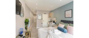 a living room with a white couch and a kitchen at Nestled Nook: Charming Studio For Couples in London